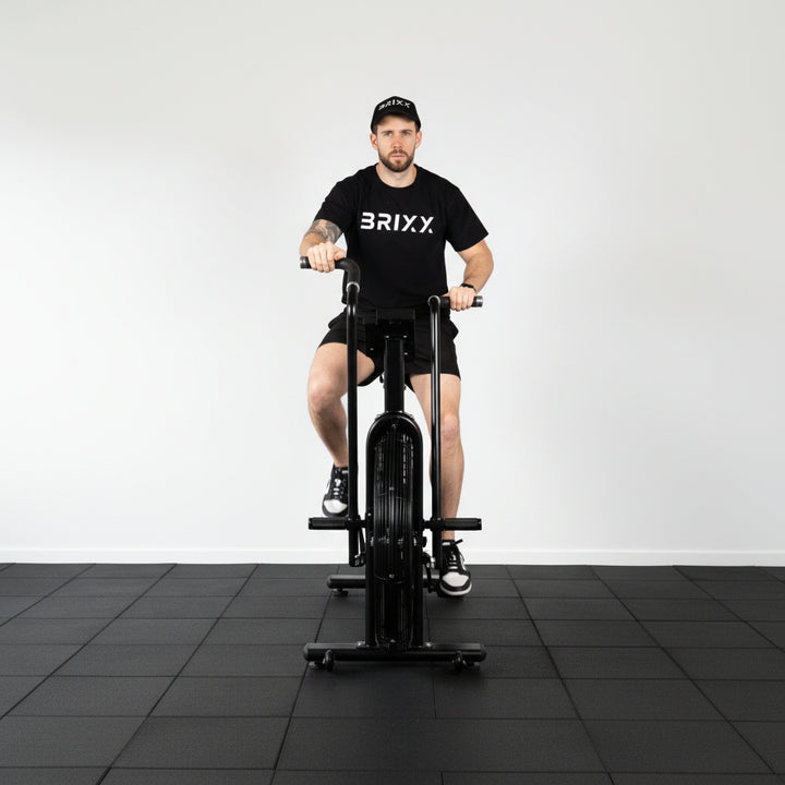 Person using a black exercise bike with 'BRIXX' branding on a white background